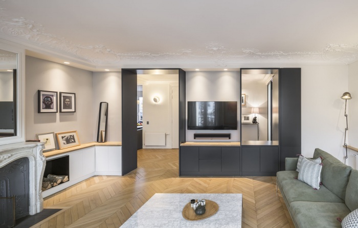 Boulainvillers : Le meuble sur mesure du salon intègre à la fois l'encadrement de l’ouverture nouvellement percée et un meuble TV. Ce travail d’ouverture laisse voir l’existence de plusieurs plans et arrières-plans dans l’appartement.